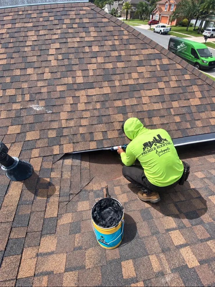 Premier Roofing crew member performing a roof tune-up with the company van parked nearby