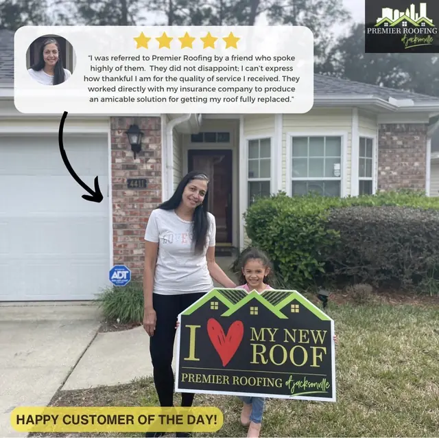 Happy customers holding a Premier Roofing sign outside their home